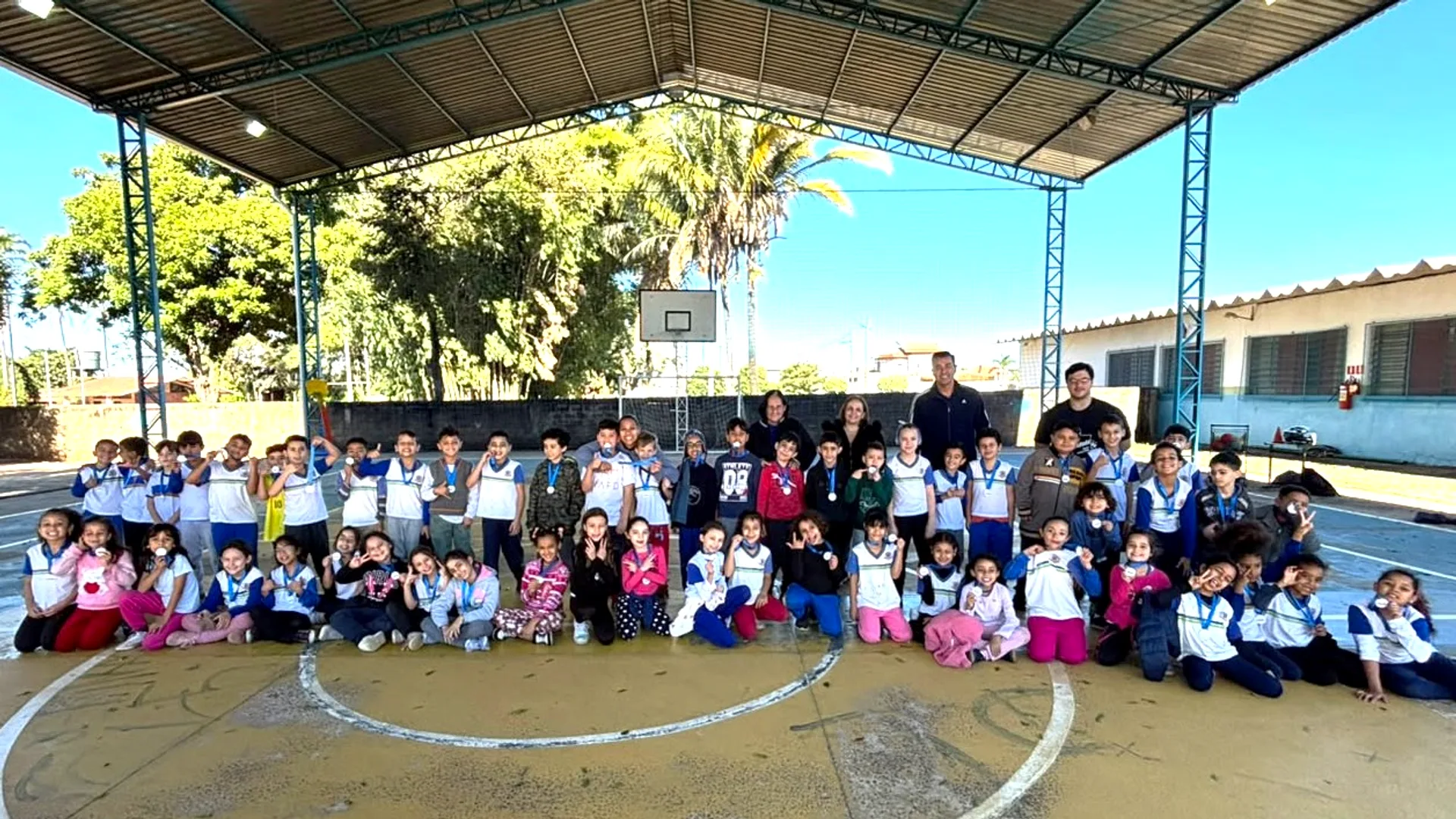 Alunos e professores posam com medalhas dos Jogos Escolares 2026 em quadra coberta de escola em Nova Odessa.
