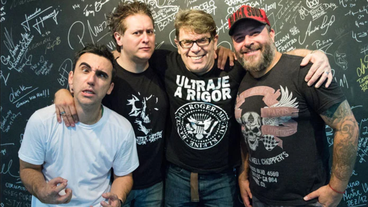 Integrantes da banda de rock Ultraje a Rigor reunidos e sorrindo em estúdio