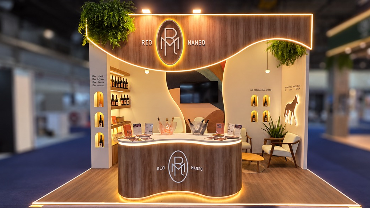 Estande da Vinícola Rio Manso na feira ProWine com iluminação acolhedora e garrafas em exibição