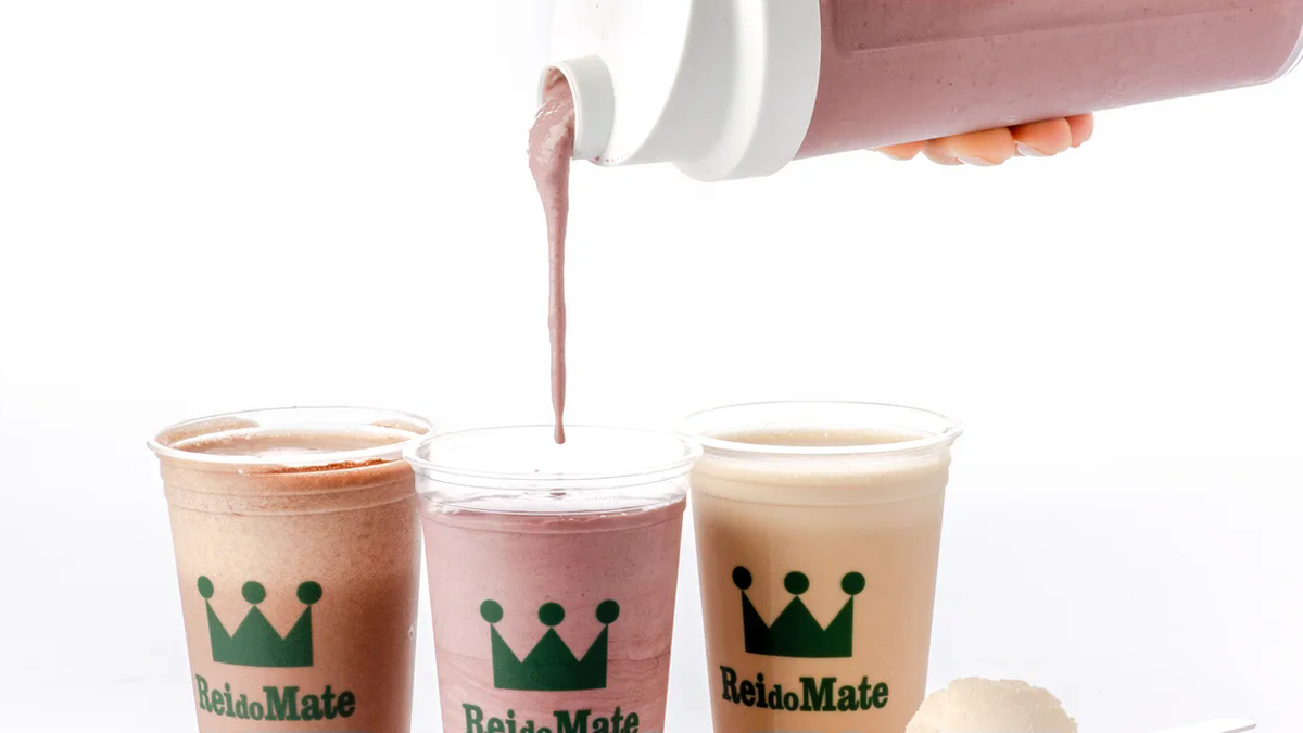 Copos da marca Rei do Mate com bebidas proteicas sendo servidas por coqueteleira