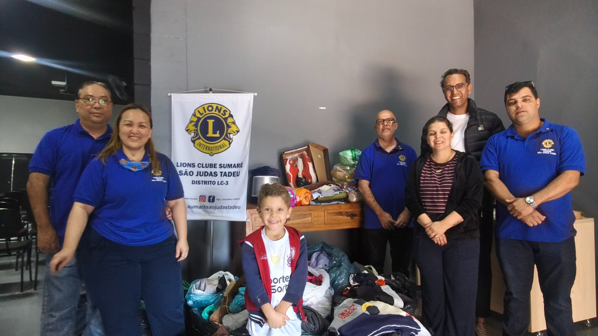 Integrantes do Lions Clube Sumaré São Judas Tadeu ao lado de roupas e agasalhos arrecadados