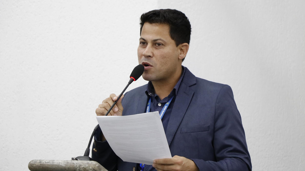 Vereador Edson Silva de terno azul no púlpito da Câmara Municipal de Monte Mor segurando documento oficial