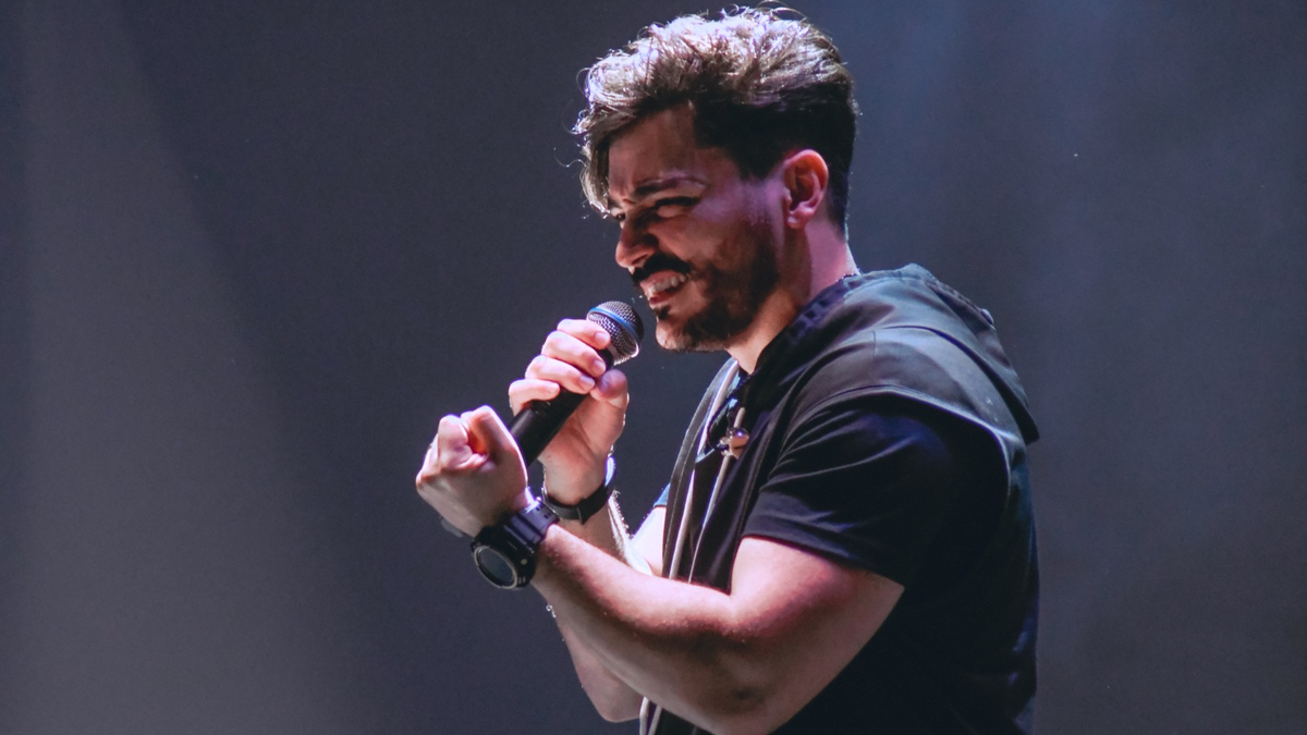 Thiago Brado canta ao microfone durante uma apresentação.
