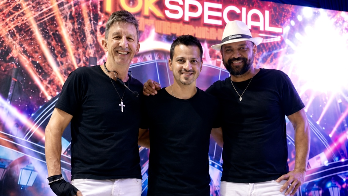 Três integrantes da Banda Tok Especial posam diante de painel do grupo